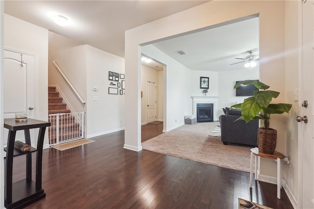 living room featuring hardwood / wood-style flooring, a fireplace, visible vents, baseboards, and stairway