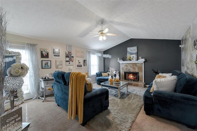 living room featuring a stone fireplace, lofted ceiling, ceiling fan, light carpet, and a textured ceiling