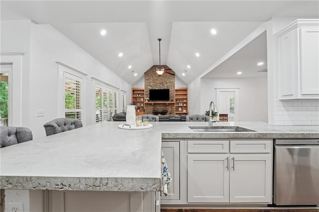 2945 Ashbyrn Ct, Buford, GA 30519 - kitchen featuring dishwasher, open floor plan, a sink, a stone fireplace, and light stone counters