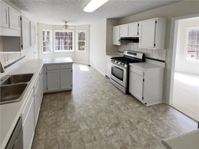 kitchen with under cabinet range hood, decorative backsplash, stainless steel appliances, a ceiling fan, and a sink