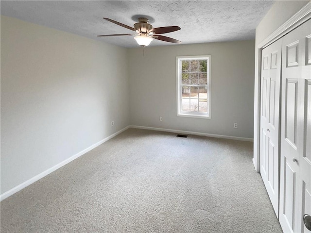 unfurnished bedroom with visible vents, a textured ceiling, a closet, carpet flooring, and baseboards