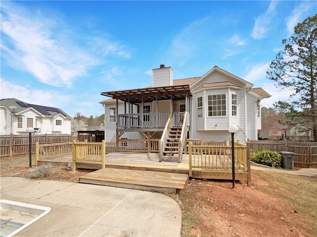 rear view of property featuring fence, a chimney, and a wooden deck