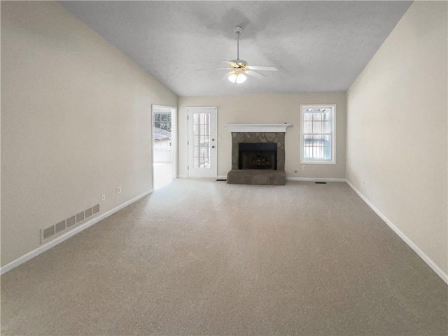 unfurnished living room with a ceiling fan, visible vents, baseboards, a stone fireplace, and vaulted ceiling