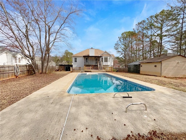 view of swimming pool featuring an outbuilding, a deck, a patio, a fenced backyard, and a fenced in pool