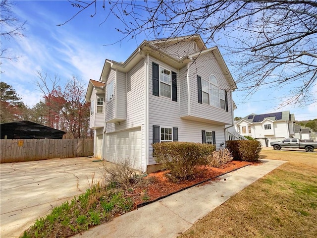 view of side of property featuring fence, a garage, and driveway