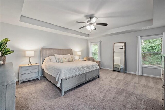 carpeted bedroom featuring a raised ceiling and ceiling fan