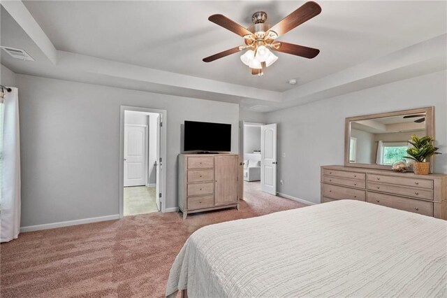 bedroom featuring a raised ceiling, ceiling fan, and light colored carpet