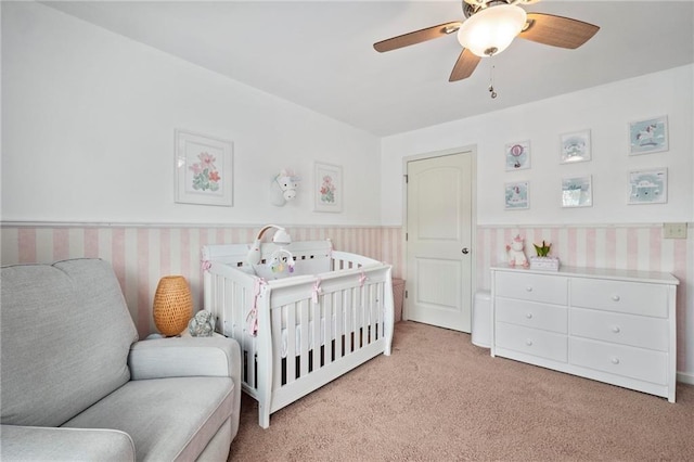 bedroom with ceiling fan, light carpet, and a crib