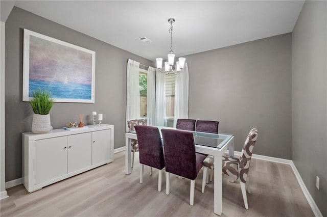 dining space featuring light hardwood / wood-style flooring and an inviting chandelier