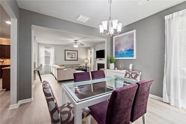 dining space featuring ceiling fan with notable chandelier and light hardwood / wood-style floors