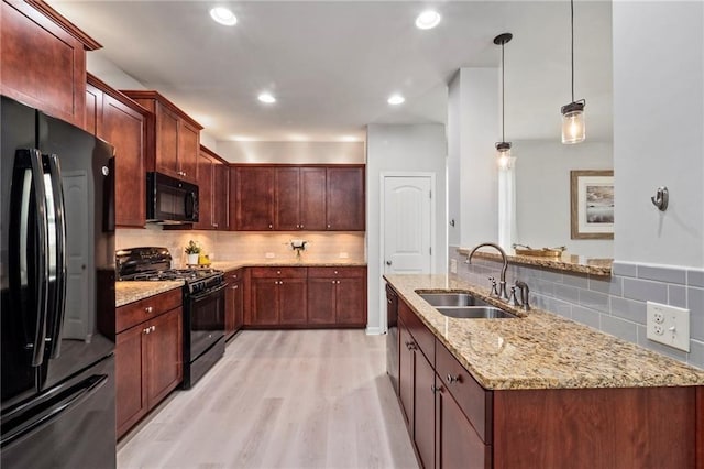 kitchen featuring black appliances, sink, light hardwood / wood-style flooring, and tasteful backsplash