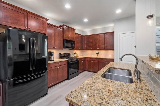 kitchen with light stone countertops, sink, black appliances, pendant lighting, and decorative backsplash