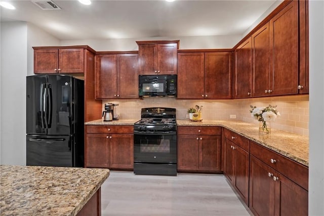 kitchen featuring black appliances, backsplash, light stone countertops, and light wood-type flooring