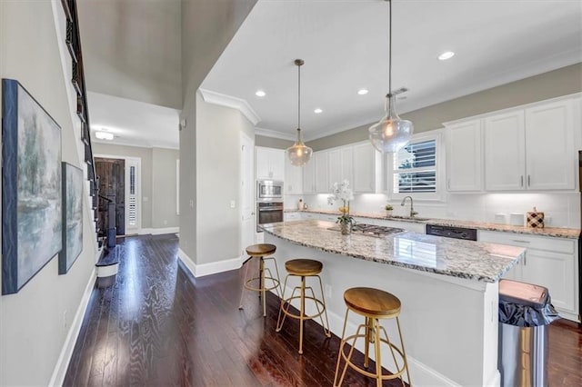 kitchen with decorative light fixtures, sink, white cabinets, a center island, and stainless steel appliances