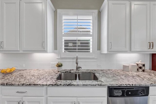 kitchen featuring sink, backsplash, stainless steel dishwasher, and white cabinets