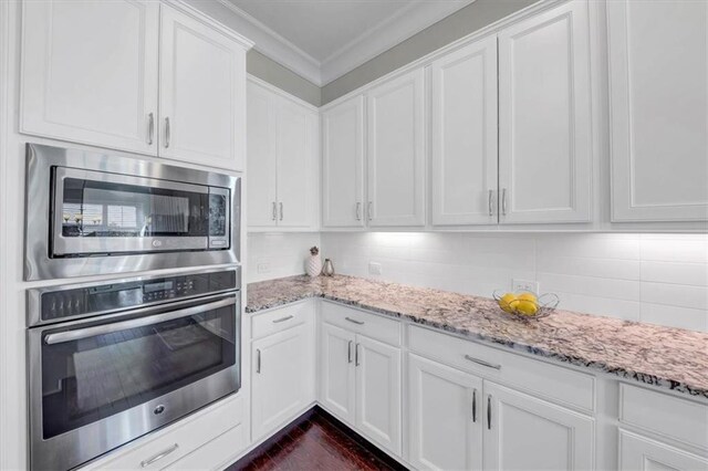 kitchen with stainless steel appliances, light stone countertops, decorative backsplash, and white cabinets