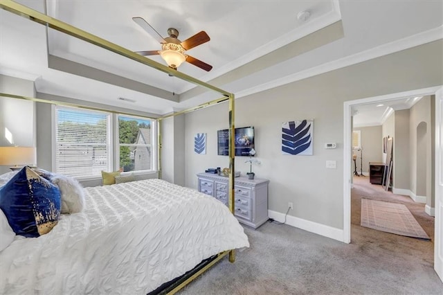 carpeted bedroom with a raised ceiling, ornamental molding, and ceiling fan