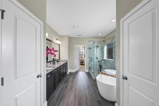 bathroom featuring hardwood / wood-style flooring, vanity, and separate shower and tub