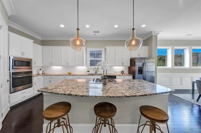 kitchen featuring pendant lighting, appliances with stainless steel finishes, a center island, and white cabinets