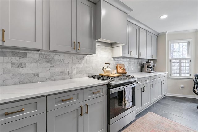 kitchen featuring gray cabinetry, decorative backsplash, light stone countertops, and gas stove