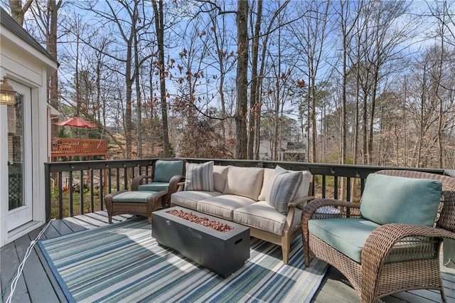 wooden terrace featuring an outdoor living space with a fire pit