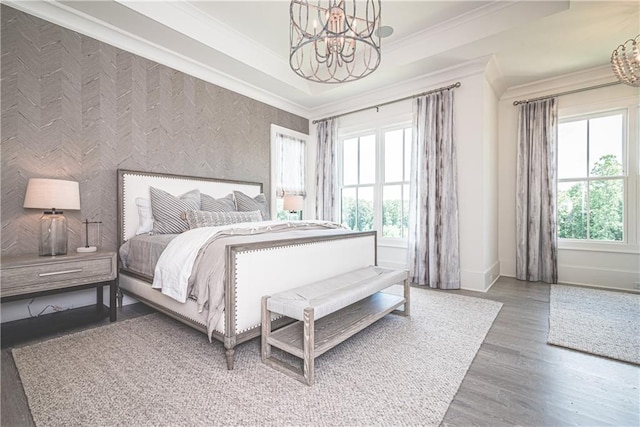 bedroom with a raised ceiling, hardwood / wood-style floors, a chandelier, and ornamental molding