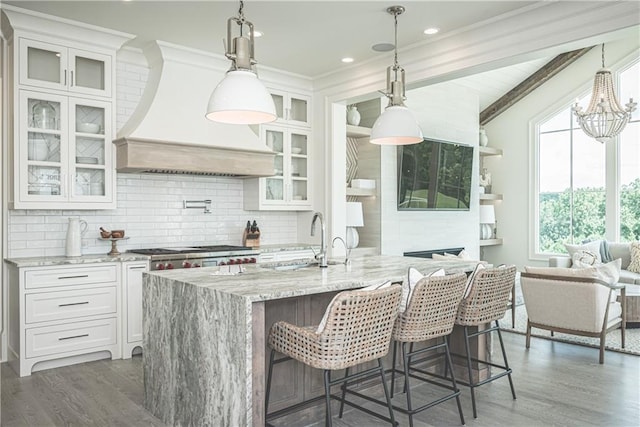 kitchen featuring premium range hood, white cabinets, hanging light fixtures, and dark hardwood / wood-style floors