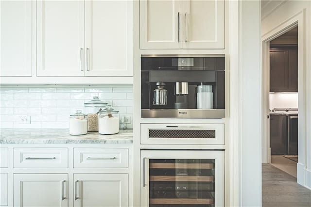 bar with light stone countertops, white cabinets, and beverage cooler