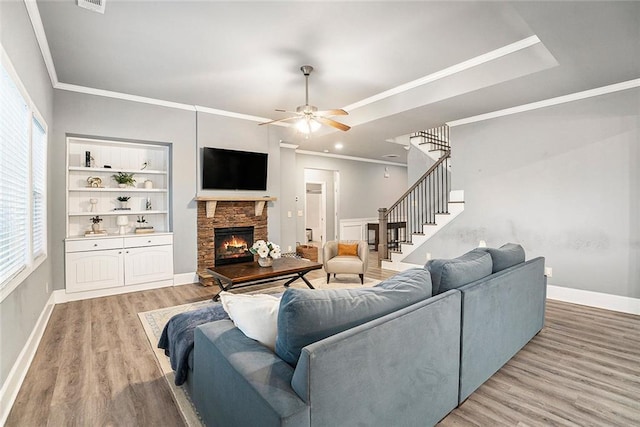 living room with a fireplace, hardwood / wood-style floors, ceiling fan, and ornamental molding