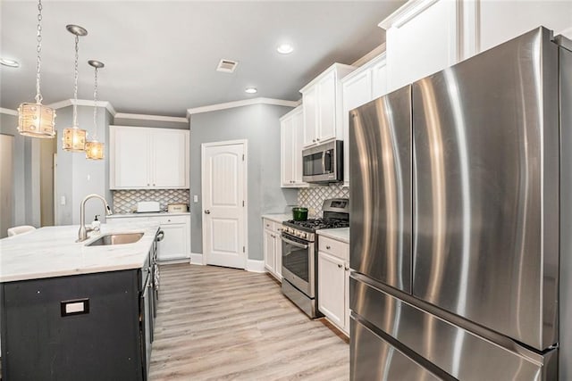 kitchen featuring stainless steel appliances, sink, pendant lighting, a center island with sink, and white cabinetry