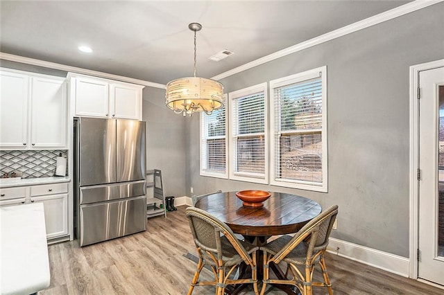 dining area featuring ornamental molding, light hardwood / wood-style floors, and a notable chandelier