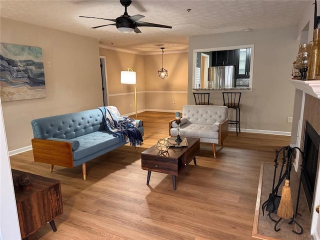 living room with hardwood / wood-style flooring, ceiling fan, and a textured ceiling