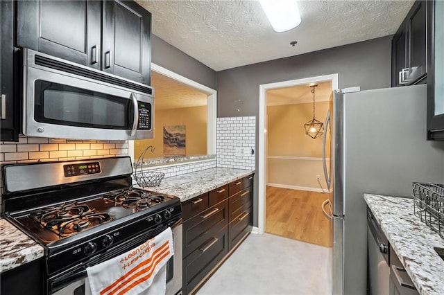 kitchen with light stone counters, appliances with stainless steel finishes, backsplash, and pendant lighting