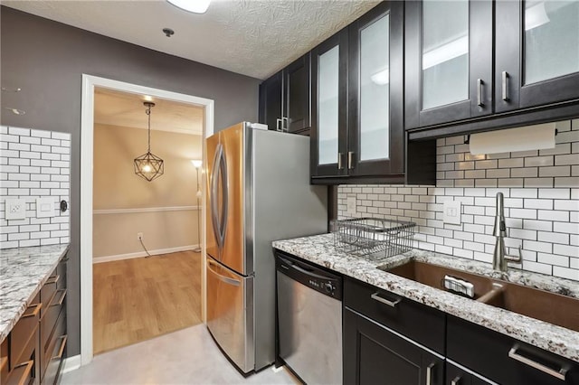 kitchen with sink, hanging light fixtures, light hardwood / wood-style flooring, stainless steel appliances, and light stone countertops