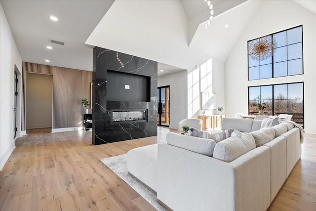 living room with a premium fireplace, high vaulted ceiling, and light wood-type flooring