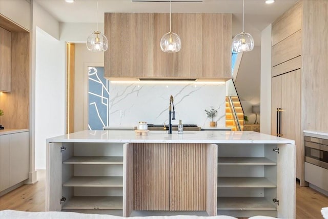 kitchen with an island with sink and light brown cabinetry