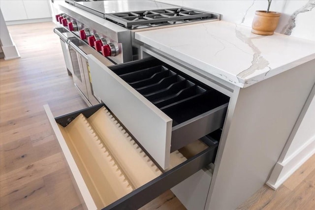 kitchen with white cabinetry, high end stove, and light hardwood / wood-style floors