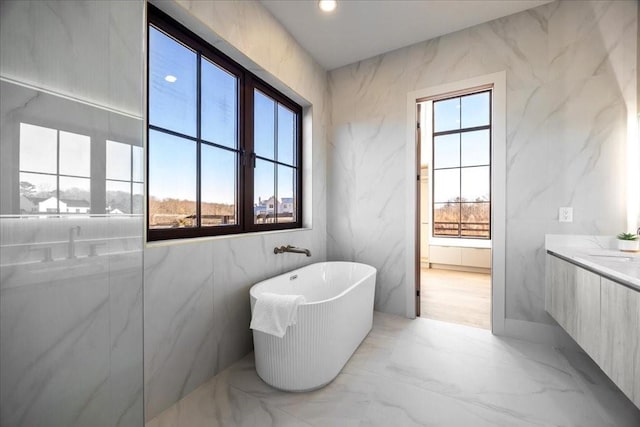 bathroom with a washtub, vanity, and a healthy amount of sunlight