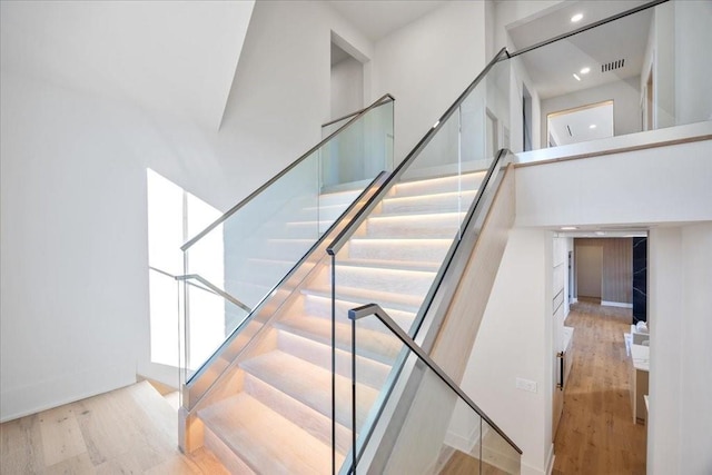 staircase with hardwood / wood-style flooring and a towering ceiling