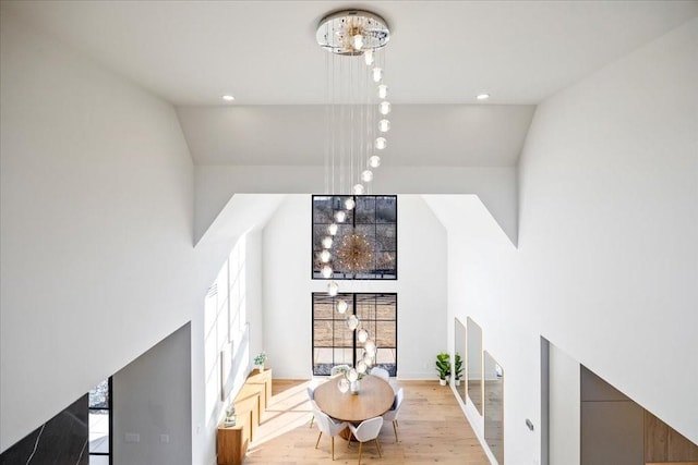 dining area featuring light hardwood / wood-style flooring, vaulted ceiling, and an inviting chandelier