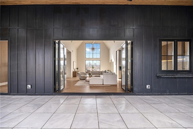 entryway with lofted ceiling, light tile patterned floors, and wooden walls