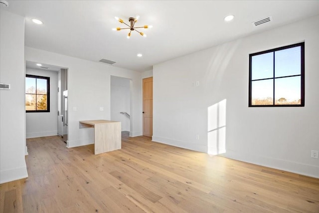 unfurnished room featuring a chandelier and light hardwood / wood-style flooring