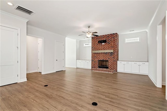 unfurnished living room featuring ceiling fan, crown molding, light hardwood / wood-style flooring, and a brick fireplace