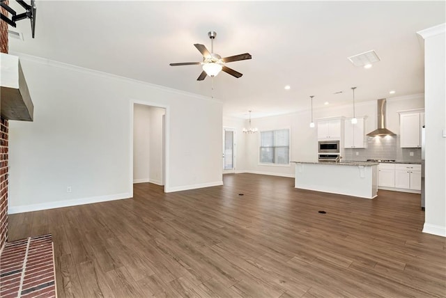 unfurnished living room with ceiling fan with notable chandelier, dark wood-type flooring, baseboards, and crown molding