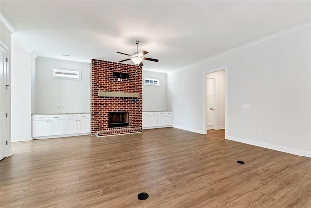 unfurnished living room with baseboards, light wood-style flooring, ceiling fan, ornamental molding, and a fireplace