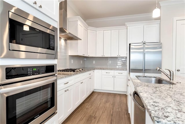 kitchen featuring sink, wall chimney exhaust hood, pendant lighting, decorative backsplash, and appliances with stainless steel finishes