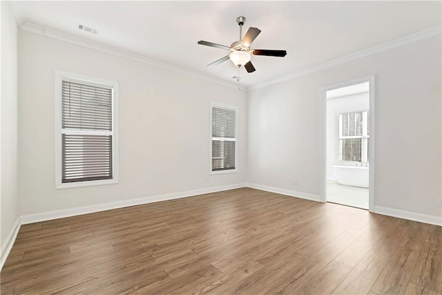 empty room featuring baseboards, wood finished floors, visible vents, and crown molding