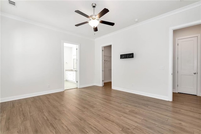 spare room with baseboards, light wood-style flooring, visible vents, and crown molding