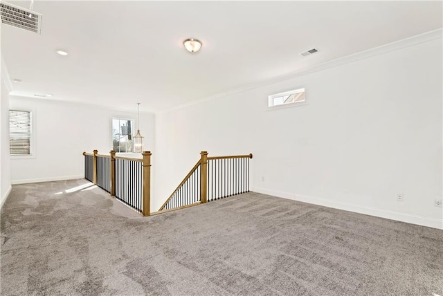 carpeted empty room featuring visible vents, crown molding, and baseboards