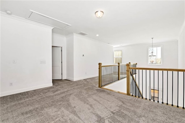 spare room with carpet floors, ornamental molding, attic access, and baseboards